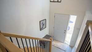 A staircase with a wooden handrail and a door at the bottom leading outside. - Stylish, Modern 3BR in Moncton (Moncton)