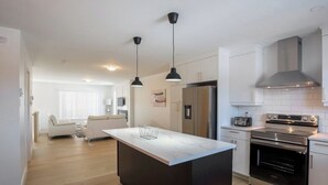 A modern kitchen with a central island, stainless steel appliances, and pendant lighting. - Stylish, Modern 3BR in Moncton (Moncton)