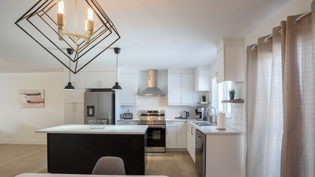 A modern kitchen with white cabinets, stainless steel appliances, and a central island. - Stylish, Modern 3BR in Moncton (Moncton)