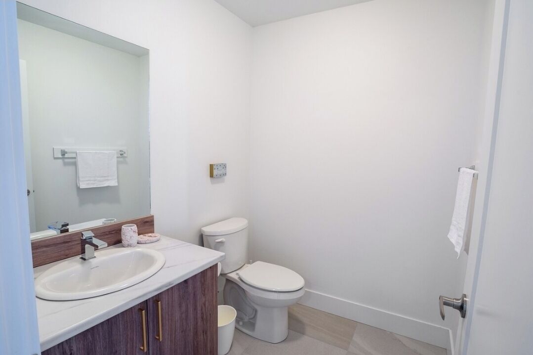 Ein kleines, modernes Badezimmer mit einem weißen Waschbecken, einem Spiegel, einer Toilette und einer Duschkabine.