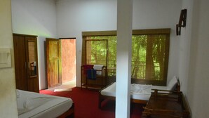 Una habitación con dos camas, una mesa de madera y una ventana con vistas a árboles.