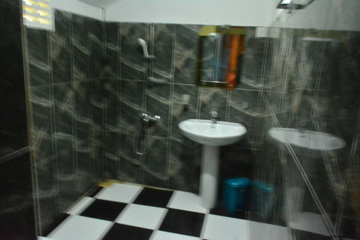 Un baño con suelo a cuadros blanco y negro, un lavabo blanco y un espejo encima.