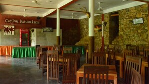 Un restaurante con mesas y sillas de madera, un muro de piedra y un ventilador de techo.