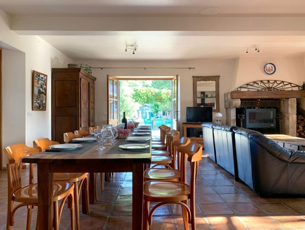 A dining area with a long table set for a meal, a bar area with a television, and a view of the outdoors.