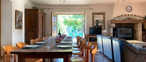 A dining area with a long table set for a meal, a bar area with a television, and a view of the outdoors.