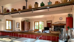 Une cuisine avec un plan de travail rouge recouvert de carreaux, un évier à deux bacs, un mixeur et une étagère contenant divers ustensiles de cuisine.