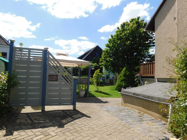 A paved pathway leading to a gated entrance with a sign reading "Königin's Garden". - 1-Bedroom Apartment in Zierow (Zierow)