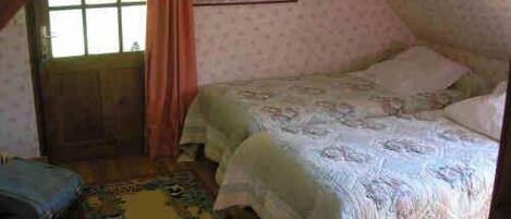 A bedroom with a bed, a window, and a door.