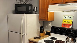 A kitchen with a white refrigerator, a stove, and wooden cabinets.