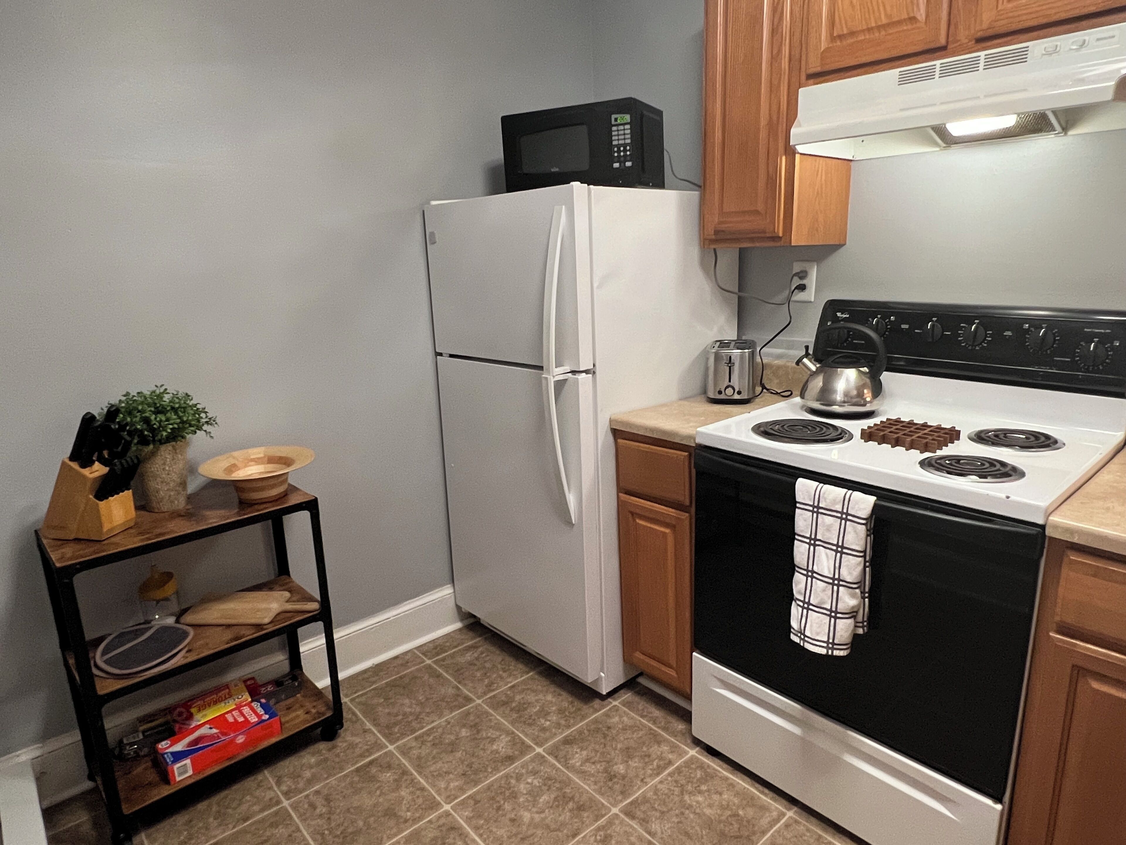 A kitchen with a white refrigerator, a black stove, and a microwave on top of the fridge.