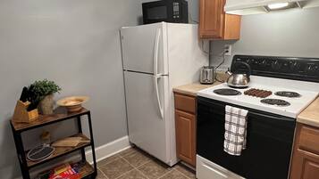 A kitchen with a white refrigerator, a black stove, and a microwave on top of the fridge.