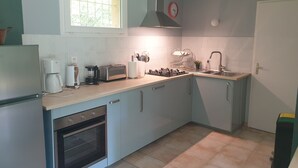 Een kleine keuken met een ingebouwde oven, koffiezetapparaat, broodrooster en een spoelbak.