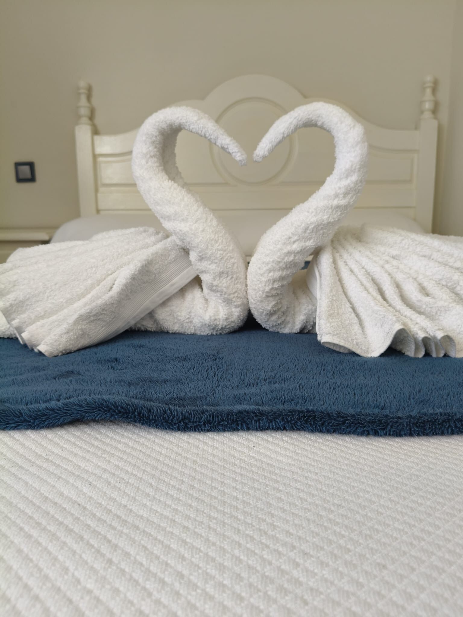 Una cama con cabecera blanca y manta azul.