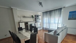 Una sala de estar moderna con comedor, sofá gris y televisor.