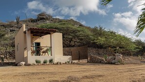 Un petit bâtiment d’un seul étage, doté d’un patio, entouré d’un paysage naturel et surplombé d’un ciel dégagé.