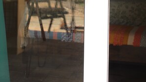 Une chambre avec un lit, une fenêtre donnant sur un espace verdoyant et une porte avec un porte-clés.