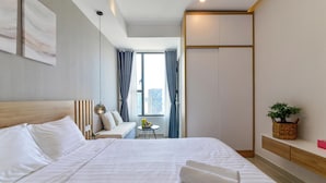 A modern hotel room with a large bed, a small table with a chair, a sofa, and a large window with curtains. - Apartment Pool Infinity View HCM (Ho Chi Minh City)