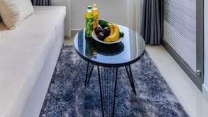 A modern hotel room with a large window, a sofa, a round table with fruit and drinks, and a view of the cityscape. - Apartment Pool Infinity View HCM (Ho Chi Minh City)