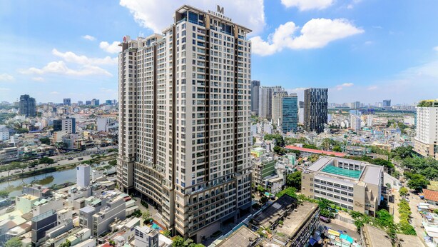 A high-rise hotel with multiple floors, surrounded by other buildings and a river. - Apartment Pool Infinity View HCM (Ho Chi Minh City)