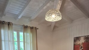 Et soveværelse med seng, gardiner, et natbord, en lampe og et billede på væggen.
