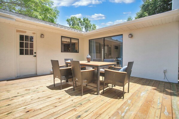 Eine Holzterrasse mit Tisch und Stühlen, einer Tür und einem Fenster.