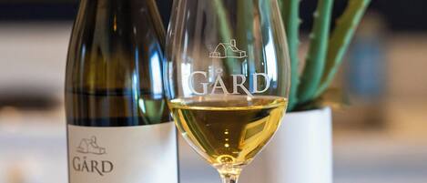 A bottle of Charles Garnier wine and a glass of white wine on a table with a woven placemat.