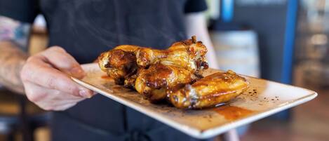 A person holding a plate of glazed chicken wings.