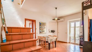 A staircase leading to a dining area with a table and chairs, a ceiling light, and a door with a window. - 1 Bedroom Apartment in Capoliveri (Capoliveri)