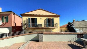A building with a balcony, a statue, and a brick pathway. - 1 Bedroom Apartment in Capoliveri (Capoliveri)