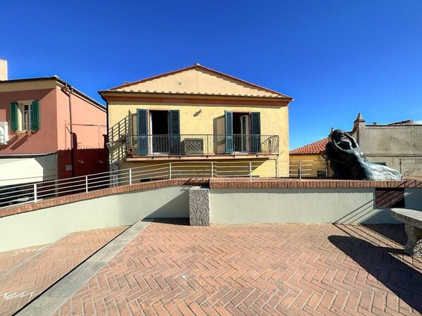 A building with a balcony, a statue, and a brick pathway.
