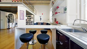 Eine moderne Küche mit einer zentralen Kochinsel, Barhocker und einer Treppe zu einer oberen Ebene.