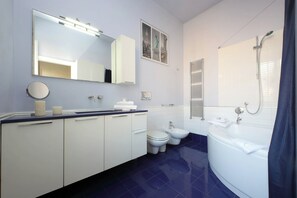 Une salle de bain moderne avec un grand miroir, des toilettes, un bidet et une baignoire.