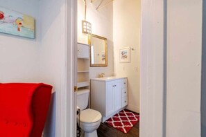 Een badkamer met een wit toilet, een wit wastafel en een rode vloerkleed.
