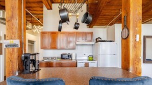 A kitchen with wooden cabinets, a granite countertop, and hanging pots. - Fun Loft with Arcade Games and River Views (Detroit)