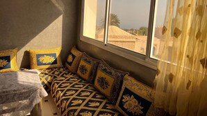 A room with a bed, a window, and a view of buildings outside.