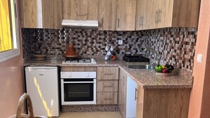 A kitchen with wooden cabinets, a built-in oven, a refrigerator, and a granite countertop.