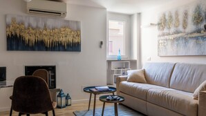 A modern living room with a beige sofa, a brown chair, a flat-screen TV, and two side tables. - Delightful apartment in Trastevere on two levels MauveSweetRhome 3 (Roma)