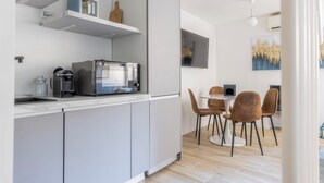 A modern kitchen with a built-in coffee machine, a dining area with a round table and chairs, and a wall-mounted air conditioner. - Delightful apartment in Trastevere on two levels MauveSweetRhome 3 (Roma)