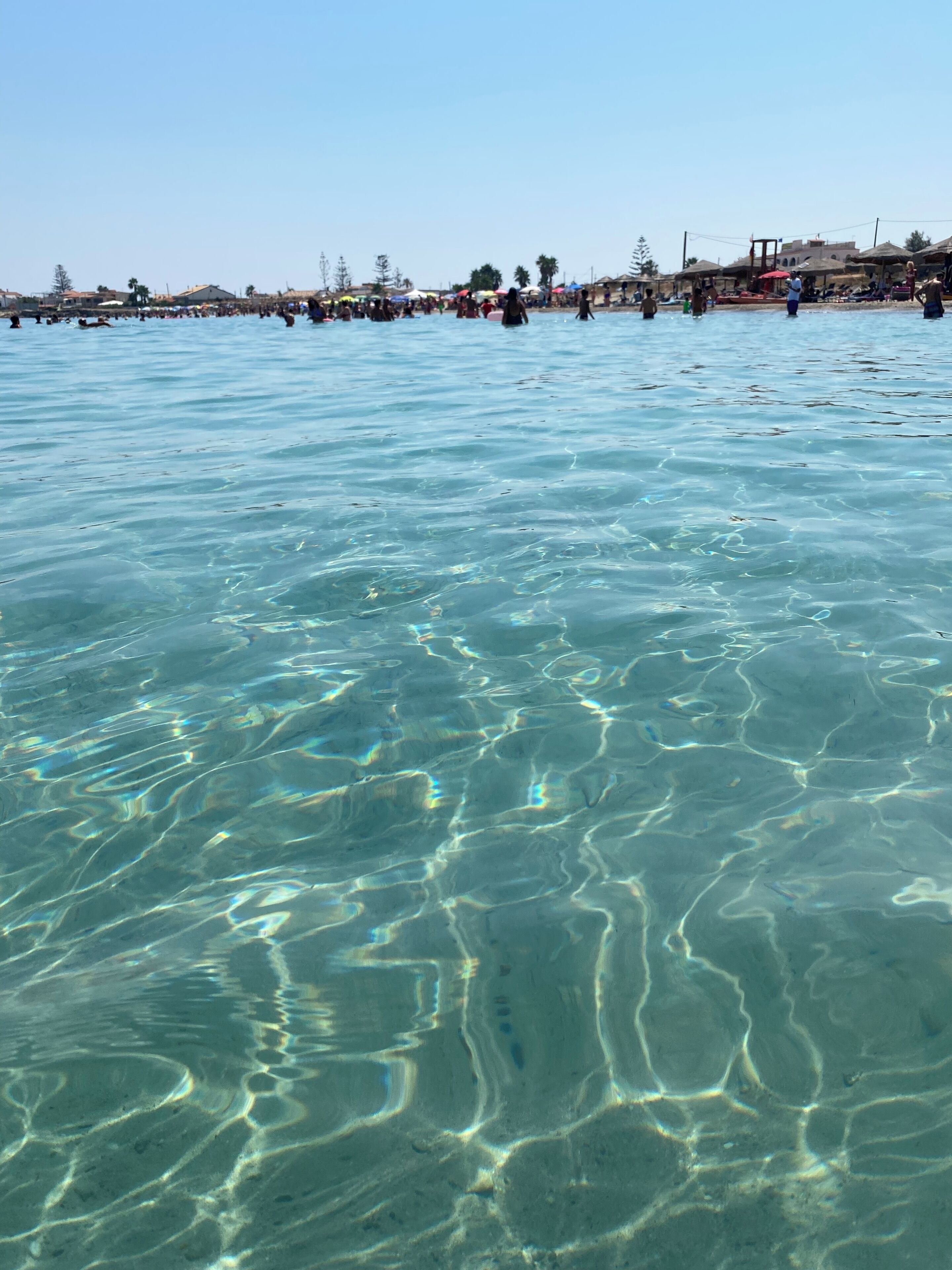 A clear view of a beach with people swimming and sunbathing.