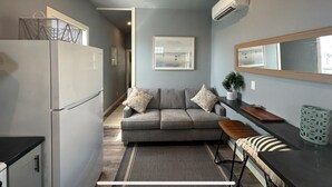 Ett kompakt kök med ett kylskåp, en matplats med en bänk, en soffa och ett litet bord.