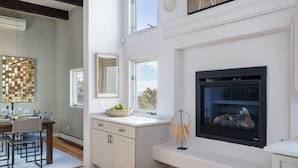 Een moderne keuken met een open haard, houten vloeren en een eethoek met een witte tafel en stoelen.