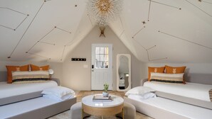 Een moderne, goed verlichte kamer met twee bedden, een ronde salontafel en een plafond met stervormige decoraties.