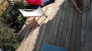 Eine Holzterrasse mit Pool, Liegestühlen und einem kleinen Tisch.