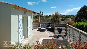Eine Terrasse mit Gartenmöbeln, einem Grill und Blick auf die umliegende Landschaft.