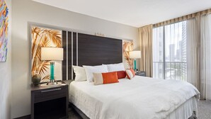 A hotel room with a large bed, two bedside tables with lamps, a headboard with the word "alona," and a large window with curtains. - Cozy Room in Heart of Waikiki (Honolulu)