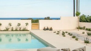 A pool area with a view of the sea, a wooden gate, and beige cushions. - Elegance Resort Rhodos (Adults Only)  (Rhodes)