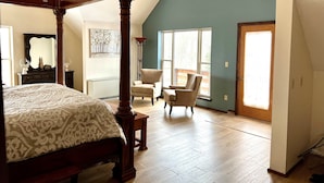 A bedroom with a four-poster bed, a chair, and a large window. - Largest Cabin Available for Rent in Cucahra! 26+ (La Veta)