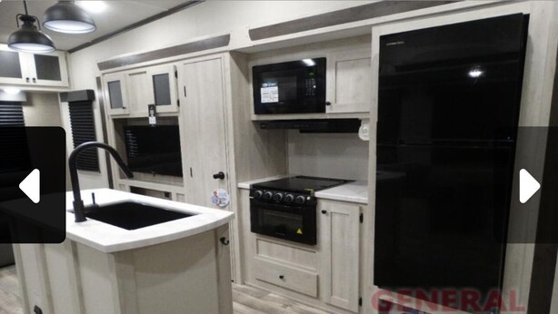 A kitchen with a sink, stove, microwave, and refrigerator.