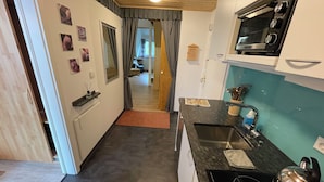 A compact kitchen with a black countertop, a built-in oven, and a sink. - Black Forest chic gallery apartment with high-quality furnishings - Mein SWH (Todtmoos)