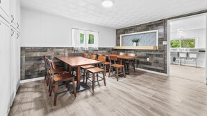 A modern kitchen with wooden cabinets, a large island, and a dining area with wooden tables and chairs. - New Listing!  Charming House at The Blue Anchor Hotel.  4 Kings, sleeps 8. (Houghton Lake)